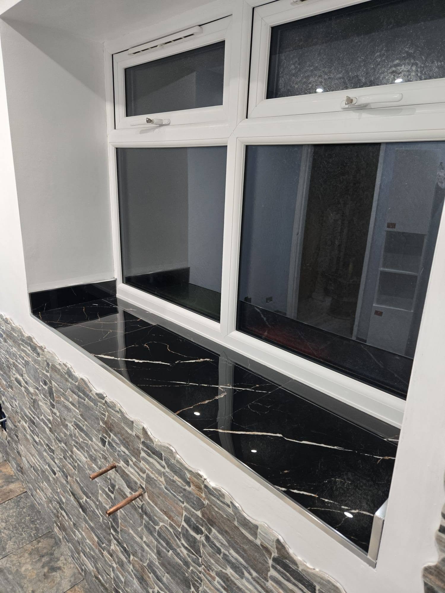 Finished bathroom with stone-effect slate wall tiles and a black marble window sill